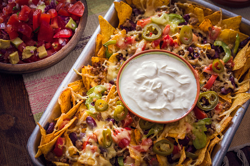 Baked Nachos Tortilla Chips with Salsa, Minced Meat and Jalapenos served with Sour Cream