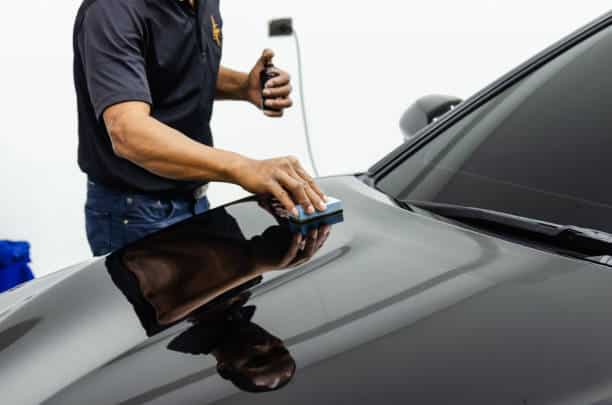 mechanic is coating ceramic glass to prevent scratches on cars.