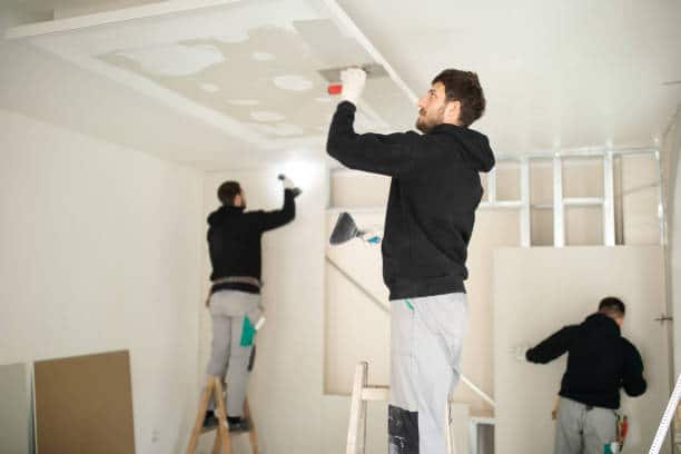 Professional construction workers installing plaster boards drywall and decorating apartment.