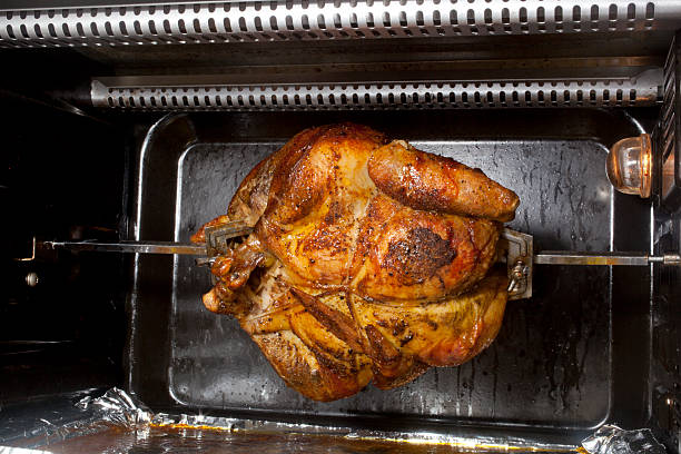 A chicken cooking on a horizontal rotisserie.