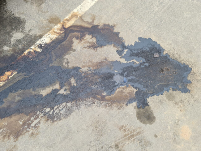 Closeup of dirty gasoline stain on asphalt background. Environmental protection concept