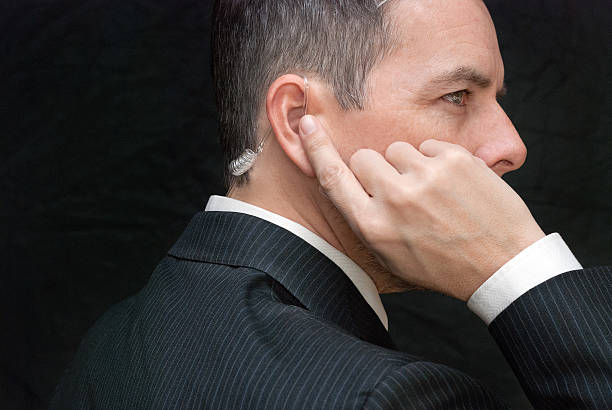 Close-up of a secret service agent listening to his earpiece, side.
